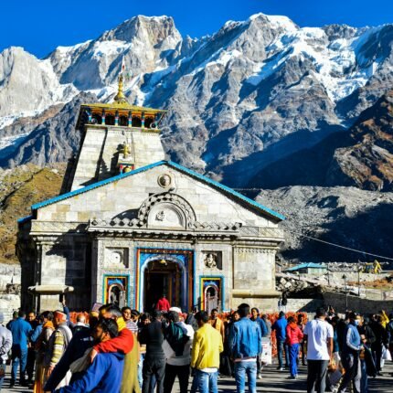 Crowd gathers at Kedarnath Temple with Himalayas backdrop, showcasing religious significance and stunning landscape.